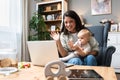 Stay at home mom working remotely on laptop while taking care of her baby. Young business mother on maternity leave trying to Royalty Free Stock Photo