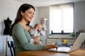 Stay at home mom working remotely on laptop while taking care of her baby. Royalty Free Stock Photo