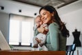 Stay at home mom working remotely on laptop while taking care of her baby. Royalty Free Stock Photo