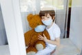 Stay at home quarantine coronavirus pandemic prevention. Sad child both in protective medical masks near windows and looks out Royalty Free Stock Photo