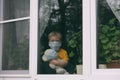 Stay at home quarantine for coronavirus pandemic prevention. Sad child and his teddy bear both in protective medical masks sits on Royalty Free Stock Photo