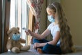 Stay at home quarantine coronavirus pandemic prevention. Sad girl and his teddy bear both in protective medical masks Royalty Free Stock Photo