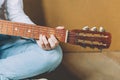 Stay Home Stay Safe. Young woman sitting at home and playing guitar, hands close up. Teen girl learning to play song and writing