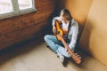 Stay Home Stay Safe. Young woman sitting in room on floor and playing guitar at home. Teen girl learning to play song and writing Royalty Free Stock Photo