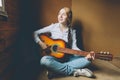 Stay Home Stay Safe. Young woman sitting in room on floor and playing guitar at home. Teen girl learning to play song