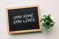 STAY HOME STAY LIVES text in white chalk handwriting on a blackboard Royalty Free Stock Photo