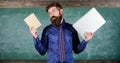 Stay modern with technology. Teacher bearded hipster holds book and laptop. Modern technologies benefit. Digital against