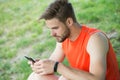 Stay online and available. Sportsman text sms on fresh air. Man relax with smartphone on green grass. Summer activity