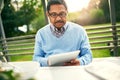 Stay online, stay up to date. an older man using a digital tablet while having his breakfast outdoors. Royalty Free Stock Photo