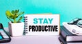 STAY PRODUCTIVE is written on a white card next to a potted flower, diaries and calculator. Organizational concept Royalty Free Stock Photo