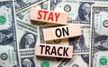 Stay on track symbol. Concept words Stay on track on wooden blocks on a beautiful background from dollar bills. Business,