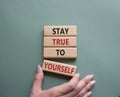 Stay True to Yourself symbol. Wooden blocks with words Stay True to Yourself. Businessman hand. Beautiful grey green background. Royalty Free Stock Photo