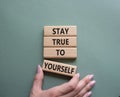 Stay True to Yourself symbol. Wooden blocks with words Stay True to Yourself. Businessman hand. Beautiful grey green background. Royalty Free Stock Photo