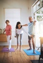 Staying balanced in their elder years. a teacher helping a senior man during a yoga class. Royalty Free Stock Photo