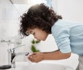 Staying clean and fresh. Shot of an adorable little boy washing his hands and mouth at a tap in a bathroom at home. Royalty Free Stock Photo