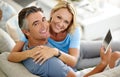 Staying connected is easier than ever. Cropped portrait of a smiling mature couple using a digital tablet while sitting Royalty Free Stock Photo