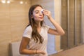 Staying fresh and clean. Beautiful young woman touching her face with sponge and smiling while standing in front of the mirror