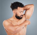 Staying fresh. Studio shot of a handsome young man applying rollon against a grey background. Royalty Free Stock Photo