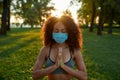 Staying healthy during coronavirus outbreak. Young mixed race woman wearing protective face mask meditating and Royalty Free Stock Photo