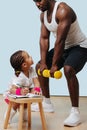 Black father doing squats, his daughter taking notes