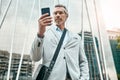 Staying organized with his day ahead. a mature businessman using a cellphone in the city. Royalty Free Stock Photo