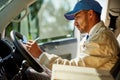 Staying on schedule requires a bit of concentration. a focused delivery man writing on a clipboard while sitting in his Royalty Free Stock Photo