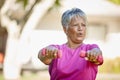 Staying strong in her senior years. a mature woman lifting dumbbells outside.