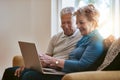 Staying tech savvy during the senior years. a happy senior couple using a laptop together on the sofa at home. Royalty Free Stock Photo