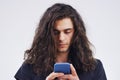 Staying touch via text. Studio shot of a young man using a mobile phone against a grey background.