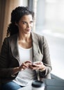 Staying in touch with whats happening in the office. a young businesswoman using a cellphone in a cafe. Royalty Free Stock Photo