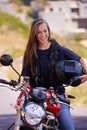 Staying true to the biker lifestyle. A beautiful young woman sitting on her motorcycle holding her helmet.