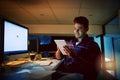 Staying true to the deadline. a young businessman using a digital tablet during a late night at work.