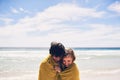 Staying warm together. an affectionate young couple wrapped in a blanket on the beach. Royalty Free Stock Photo