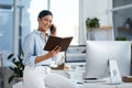 She stays absolutely dedicated to the job. a young businesswoman talking on a cellphone while going through notes in an