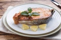 Steak baked fish salmon on a plate with lemon. Wooden table