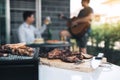 Close up grilled meats and various food on the grill and celebrations of friends who are playing guitar and sing together in their