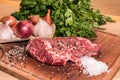 Steak of beef on a wooden board with spices pepper parsley salt onions shallots garlic Royalty Free Stock Photo