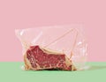 Steak in cellophane packaging on a colored background Royalty Free Stock Photo
