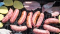 Steak on a charcoal grill outdoors close up. Tasty but unhealthy food. Sausages roasted on grill during barbecue. Horizontal view Royalty Free Stock Photo