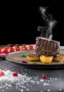 Steak Filet Mignon with Smoke. Baked Potatoes, cranberry Sauce, cherry tomatoes on a gray concrete background Royalty Free Stock Photo