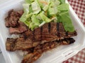 Steak, Kalbi, Side salad and white rice in a styrofoam plate Royalty Free Stock Photo