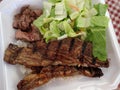 Steak, Kalbi, Side salad and white rice in a styrofoam plate Royalty Free Stock Photo