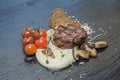 Steak with mashed potatoes, decorated with a branch of cherry tomatoes, croutons, slices of dark trout and white Royalty Free Stock Photo