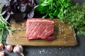 Steak meat on a wooden kitchen board, basil, garlic, rosemary, h