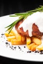 Steak medallion with French fries on a white plate. Steak is poured with white sauce