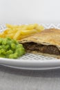 Steak and onion lattice pie with fries and mushy peas. Royalty Free Stock Photo