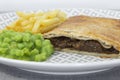 Steak and onion lattice pie with fries and mushy peas. Royalty Free Stock Photo