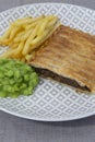 Steak and onion lattice pie with fries and mushy peas. Royalty Free Stock Photo