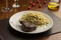 Steak with pasta tagliatelle fetuccini on plate with blurred background with tomatoes olive oil