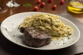 Steak with pasta tagliatelle fetuccini on plate with blurred background with tomatoes olive oil